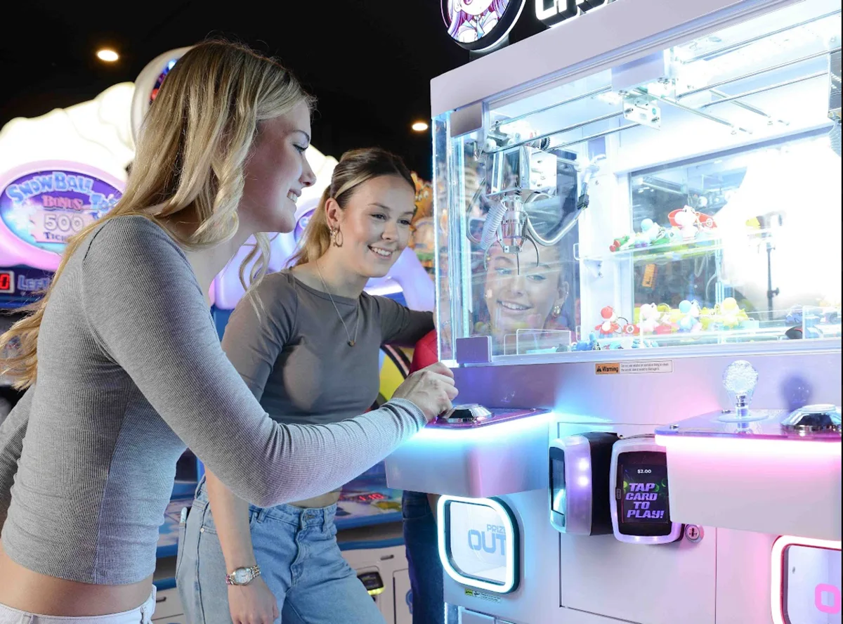 Two friends playing the claw machine in the Bendigo Bowl arcade